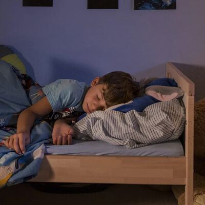 Junge schläft bei Nachtlicht-Beleuchtung friedlich in seinem Bett im Kinderzimmer