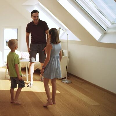 Ein Vater mit Sohn und Tochter in einem Zimmer mit Dachschrägen und Dachfenstern