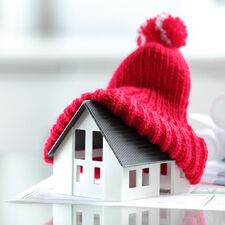Ein Modellhaus mit aufgesetzter roter Strick-Mütze auf einem Tisch