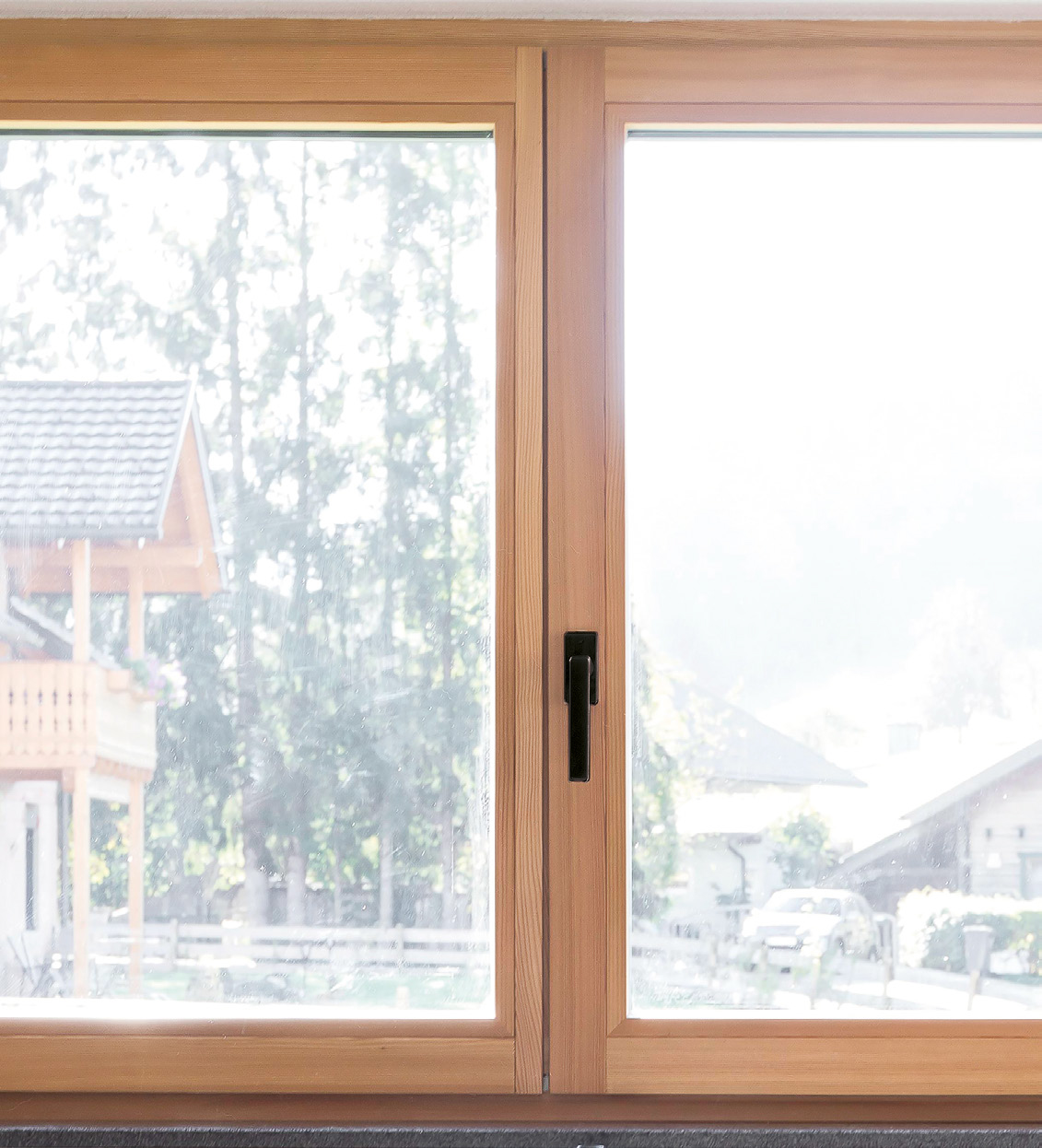 Nahaufnahme eines 2-flügeligen Holz-Fensters mit schwarzem Aluminium-Fenstergriff