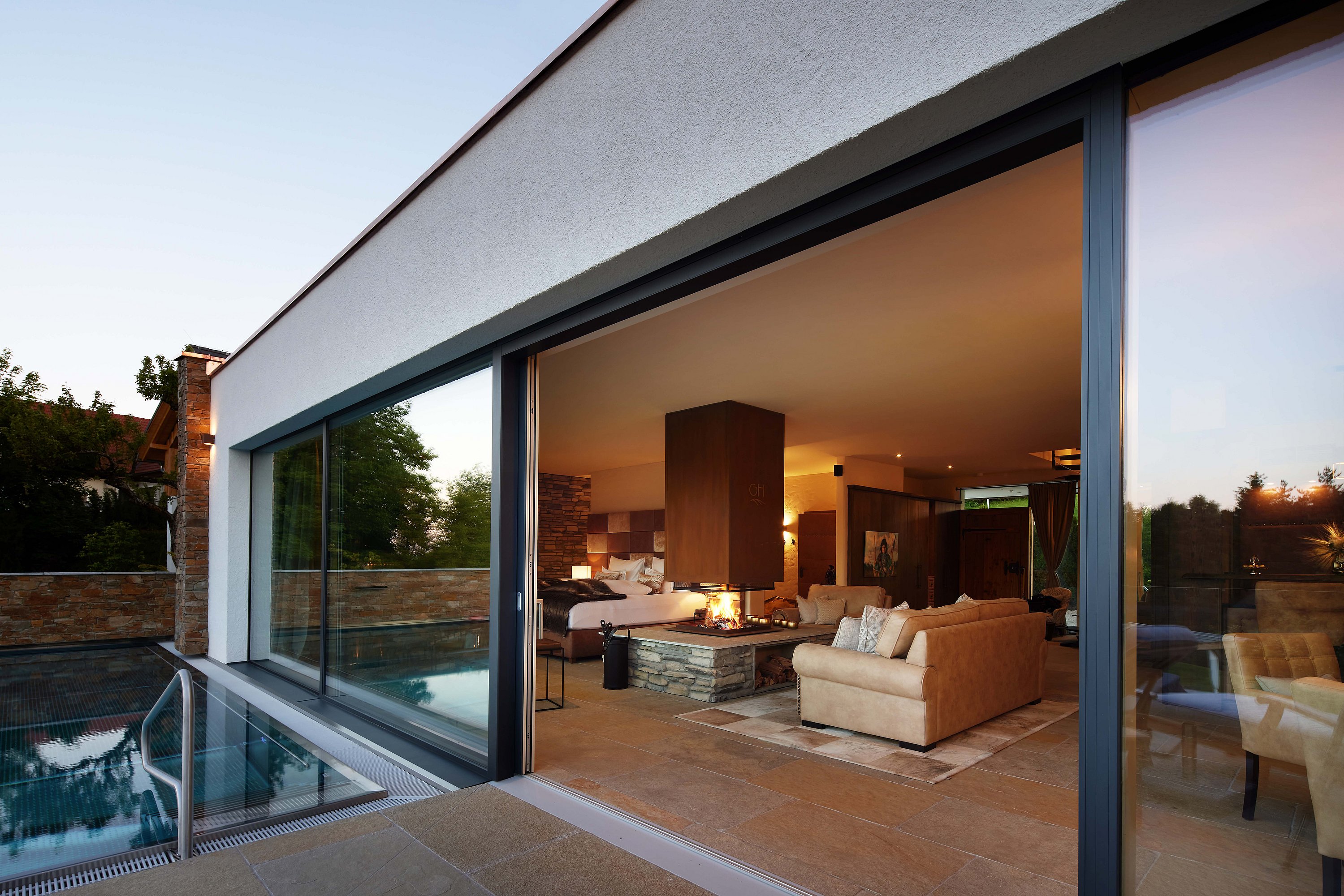 Blick von der Terrasse mit Pool durch die geöffnete Hebe-Schiebe-Anlage in eine luxuriös eingerichtete Wohnung