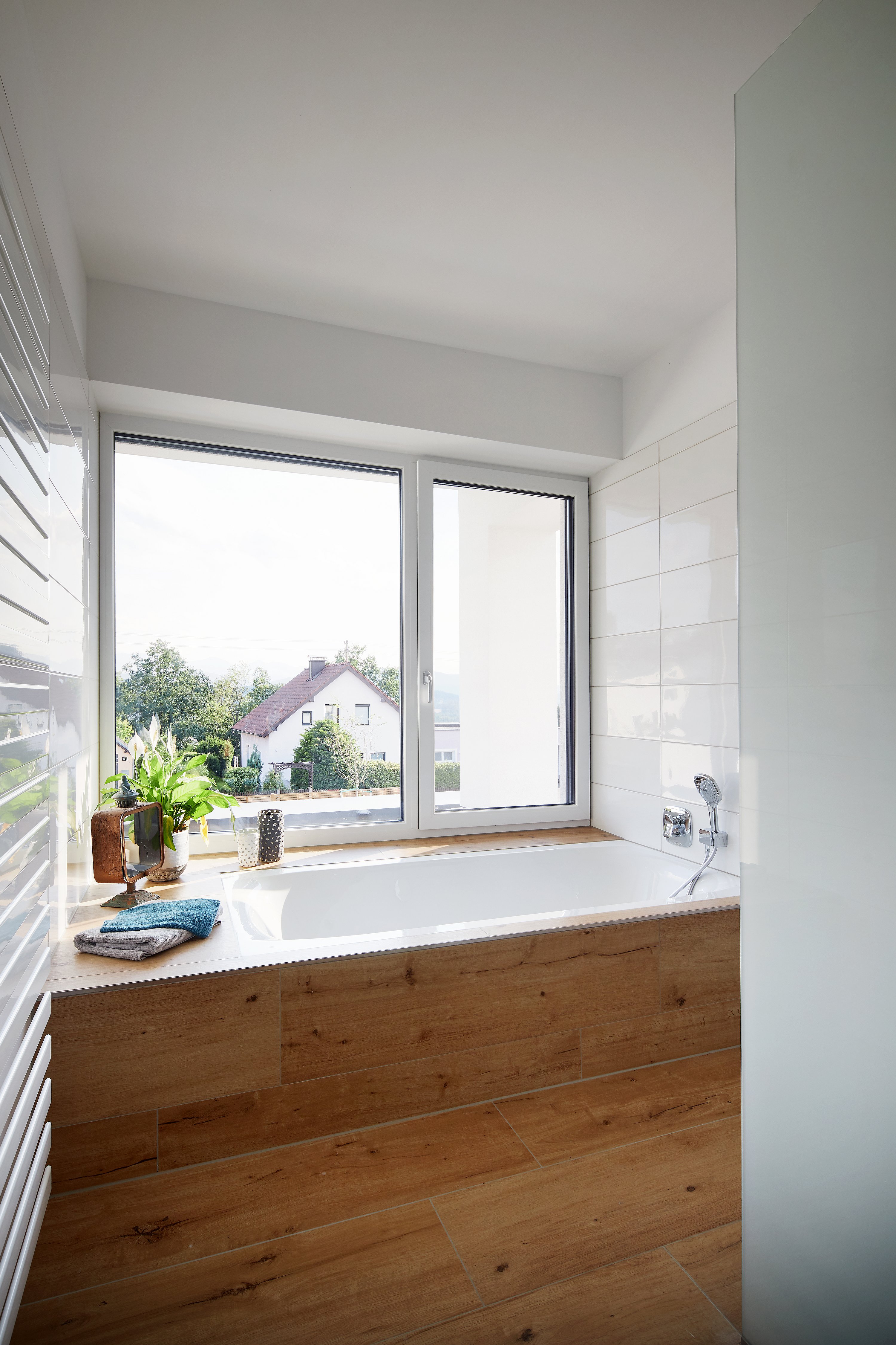 Blick in ein Badezimmer mit Badewannenpodest vor zweiflügeligem Fenster aus Kunststoff-Aluminium